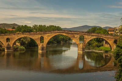 Arch bridge over river against sky