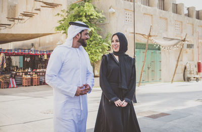 Smiling couple talking while walking on street in town