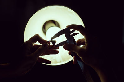 Close-up of hands on illuminated lamp