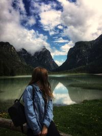 Woman looking at lake against mountain range and sky