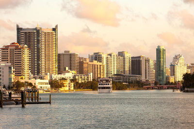 Boat moored on miami beach by buildings against during sunset