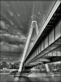 Low angle view of bridge over river in city against sky