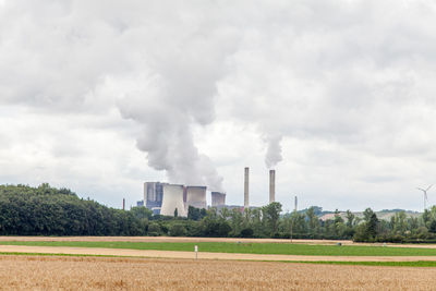 Smoke emitting from factory against sky