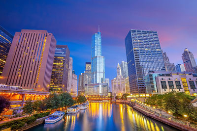 Illuminated buildings in city against sky at dusk