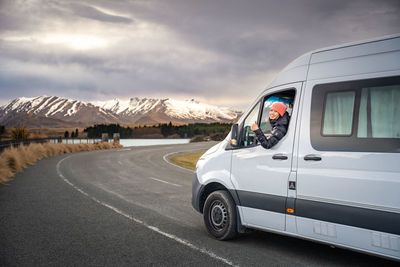 Asian women pose with her camper van for road trip vacation at new zealand south island.