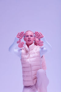 Portrait of young woman with arms crossed standing against white background