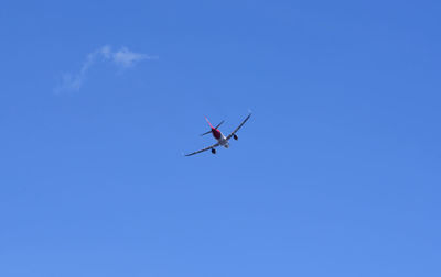 Low angle view of airplane against clear blue sky