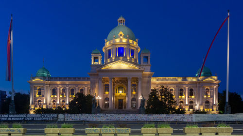 Illuminated building against blue sky at dusk
