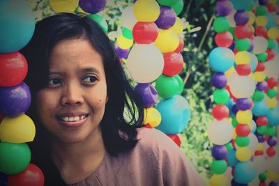 Smiling young woman standing by colorful balloons