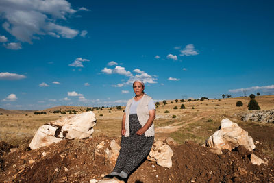 Portrait of woman standing on rock against sky