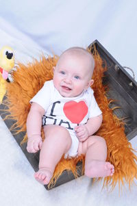 Portrait of cute smiling girl baby sitting in box