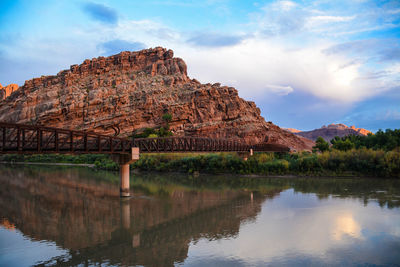Rock formation by lake against sky