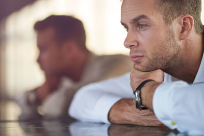 Thoughtful young businessman sitting at table in office