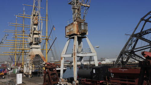 Cranes at harbor against sky