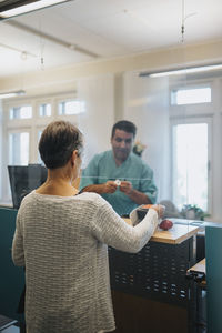 Senior female patient signing in at reception desk in hospital