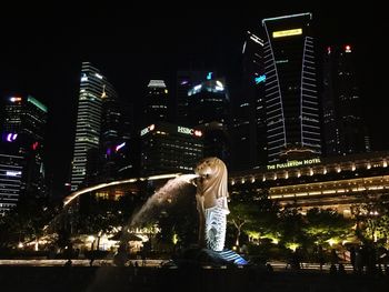 Rear view of woman standing by illuminated cityscape at night