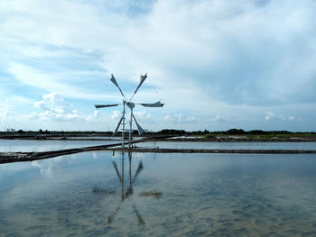 Traditional windmill on agricultural field against sky