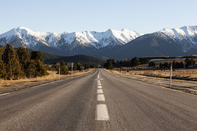 Empty road leading towards mountains against sky