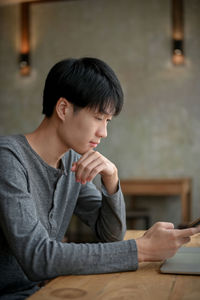 Side view of young woman using mobile phone while sitting at home