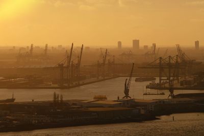 Sailboats in harbor against sky during sunset