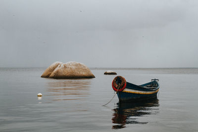 Boat moored in sea against sky