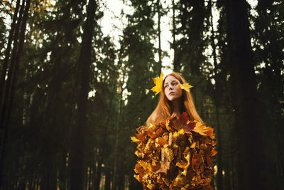 Woman standing by tree in forest