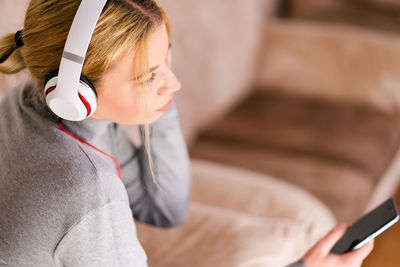 High angle view of woman listening music while sitting on sofa