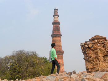 Rear view of man standing on rock against sky