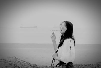 Woman standing at beach against sky