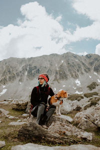 Girl standing on rock against mountains whit a beagle dog