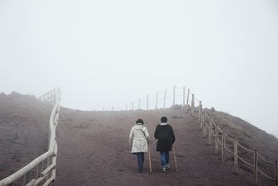 Rear view of men on road against sky
