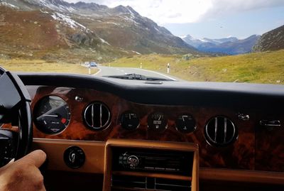 Close-up of hand on car against mountain