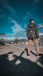 Rear view of man standing on road in city