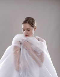 Portrait of young woman standing against white background