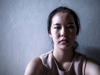 Close-up portrait of a young woman against wall