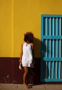 Rear view of woman standing against yellow wall