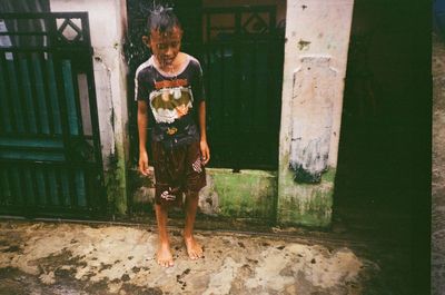 Full length of teenage boy standing against building