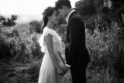 Side view of newlywed couple with face to face standing in park