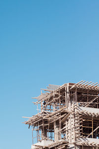 Low angle view of construction site against clear blue sky