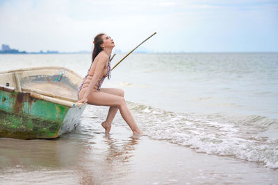 Young woman on beach against sky