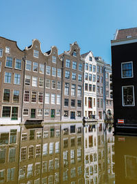 Reflection of building in canal against blue sky