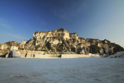 Rock formations on landscape against clear blue sky