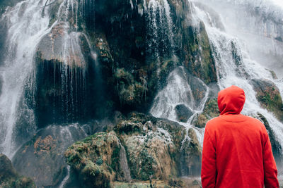 Rear view of person looking at waterfall