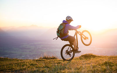 Man riding bicycle on field against sky