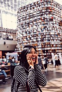 Portrait of smiling young woman using mobile phone in city