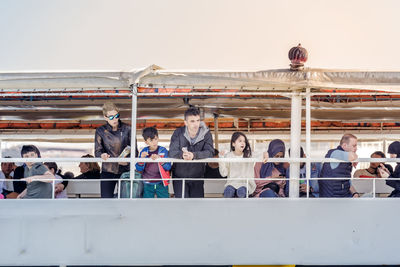 Group of people sitting on railing against the sky