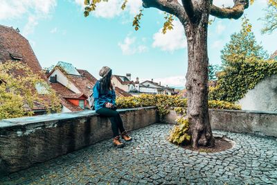 Side view of woman standing on footpath against sky