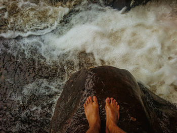 Low section of person on rock at beach