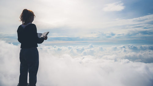 Woman standing on rock against sky