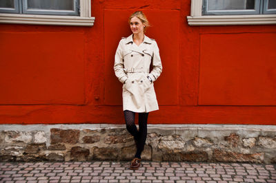 Portrait of young woman standing against brick wall